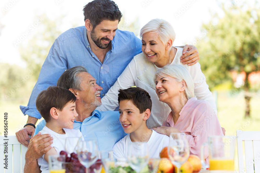 Fototapeta premium Family sitting at table outdoors, smiling 