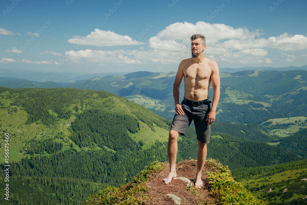 Naked athletic man standing on the mountain rock
