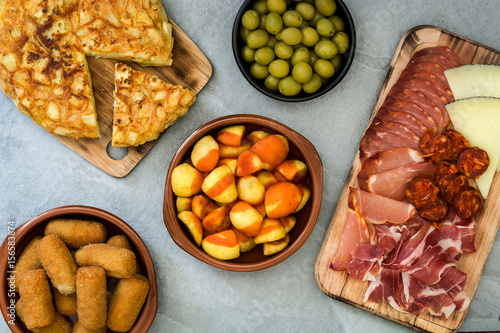 Traditional spanish tapas. Croquettes, olives, omelette, ham and patatas bravas on gray stone
 photo