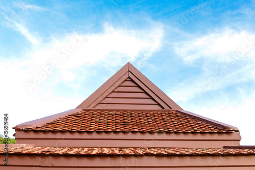 detail of wooden roof gable with clay roof tile on blue sky