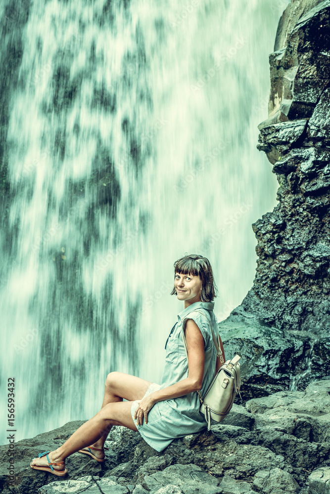 Woman on a waterfall deep in the tropical rain forest of Ubud, tropical Bali island, Indonesia. Exotic scene of tropics. Freedom concept.