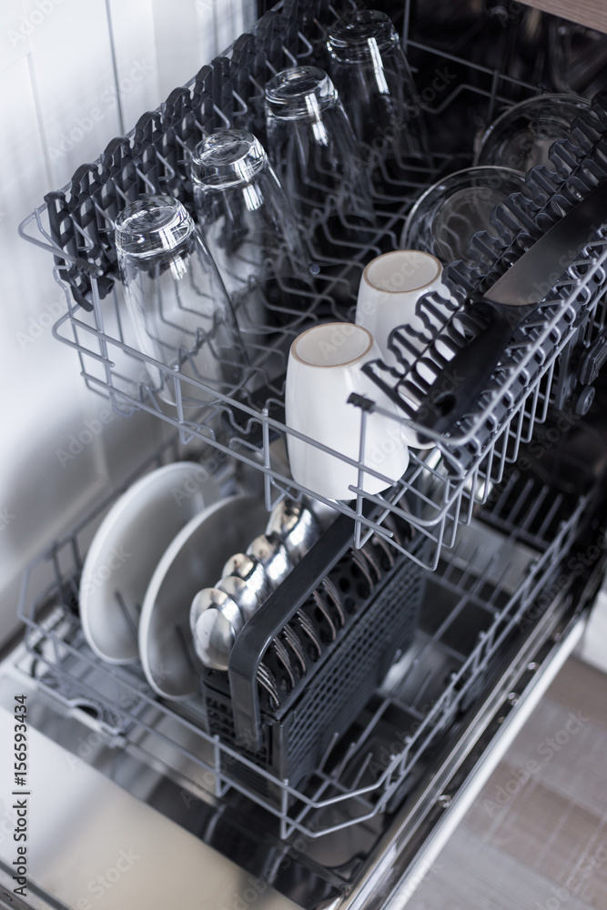 open dishwasher with clean utensils in kitchen open dishwasher with clean utensils in kitchen