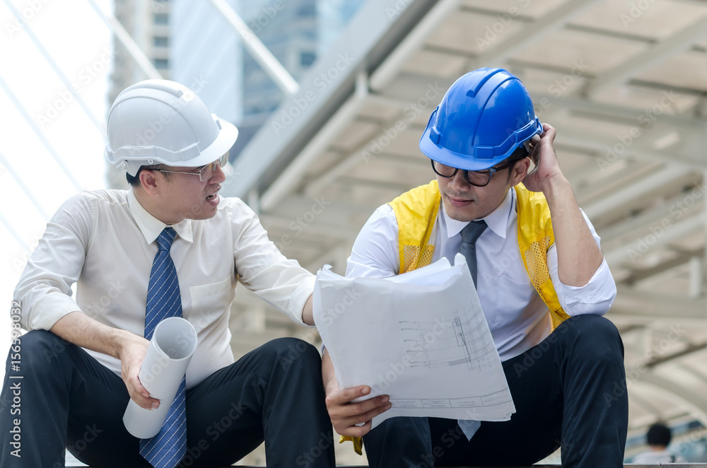 Two asian architects discussing about new project with paperwork. Two asian architects discussing about new project with paperwork.
