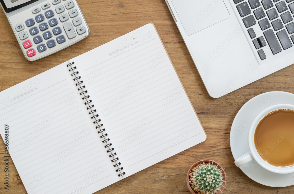 Wooden desk table with notebook, computer laptop, calculator, cactus and cup of coffee. Top view with copy space. Wooden desk table with notebook, computer laptop, calculator, cactus and cup of coffee. Top view with copy space.