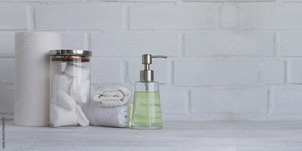 Part of spa interior. Cotton napkins, cotton pads, tissue, towels, soap and cosmetic products on a wooden table. White background and table. Copy space. Selective focus. Wide panoramic image. Part of spa interior. Cotton napkins, cotton pads, tissue, towels, soap and cosmetic products on a wooden table. White background and table. Copy space. Selective focus. Wide panoramic image.