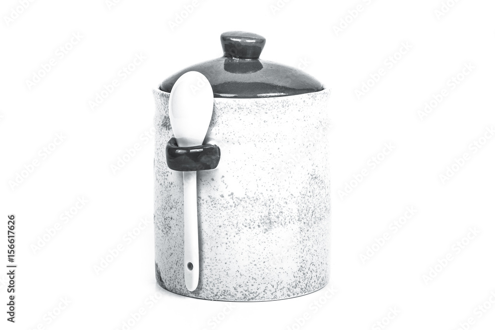 Light ceramic jar with spoon and cover on a white background. Toned Light ceramic jar with spoon and cover on a white background. Toned