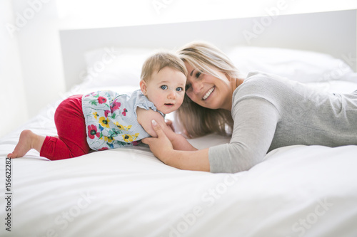 Pretty baby sit on mom in silk bed