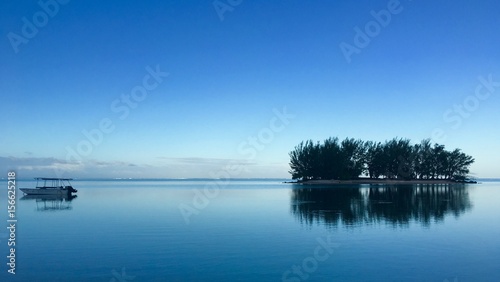 View on a small motor boat and and a small Motu in the lagoon of Moorea in the very early morning