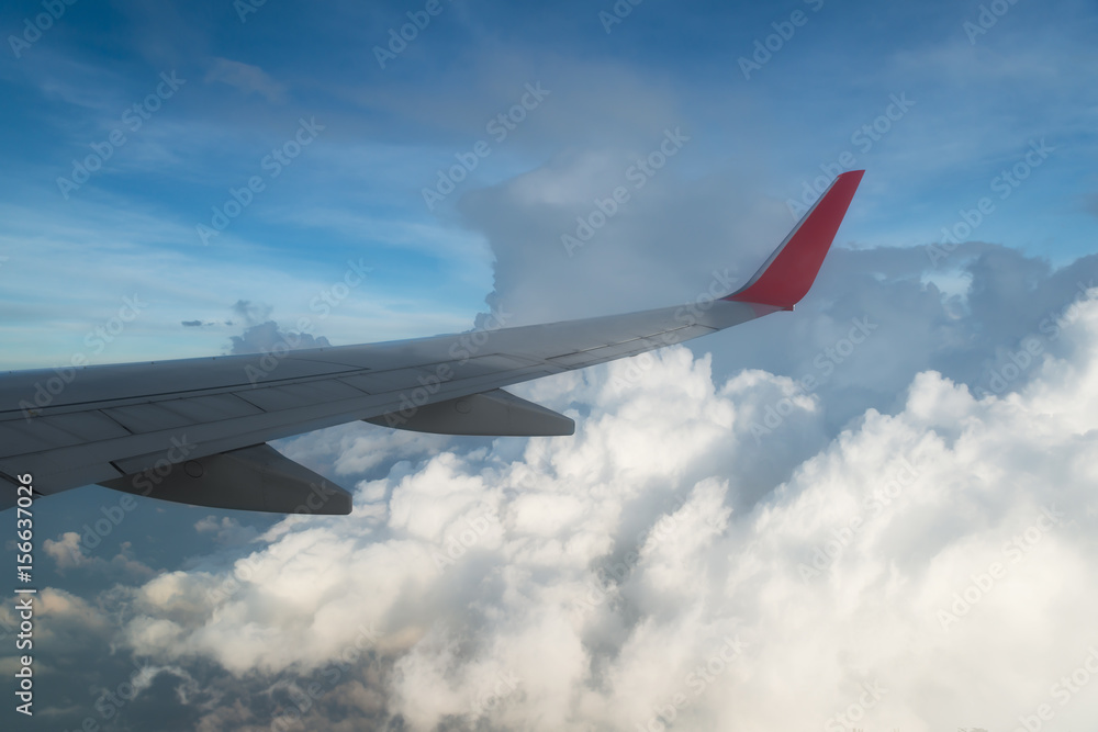 Fototapeta premium Wing of an airplane flying above the clouds. people looks at the sky from the window of the plane, using airtransport to travel.