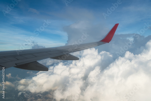 Wing of an airplane flying above the clouds. people looks at the sky from the window of the plane  using airtransport to travel.