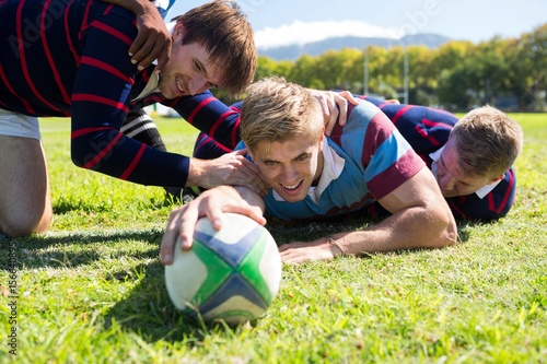 Close up of players playing rugby while lying at grassy field