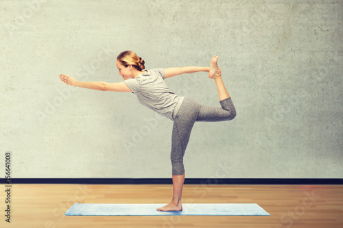 woman making yoga in lord of the dance pose on mat