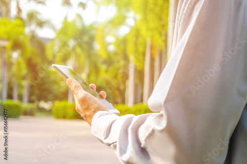 Man uses his Mobile Phone is outdoor park, close up