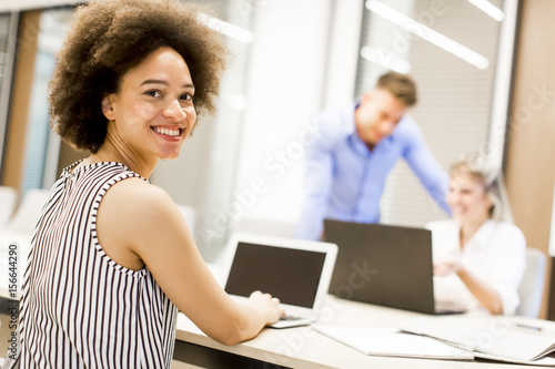 Young african american woman sitting and using laptop in a modern office