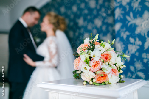 Wedding bouquet on the background of hugging bride and groom photo