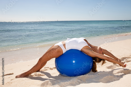 femme sportive sur la plage avec une balle de gymnastique 