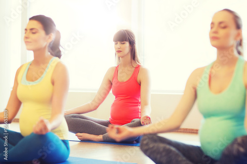 happy pregnant women exercising yoga in gym