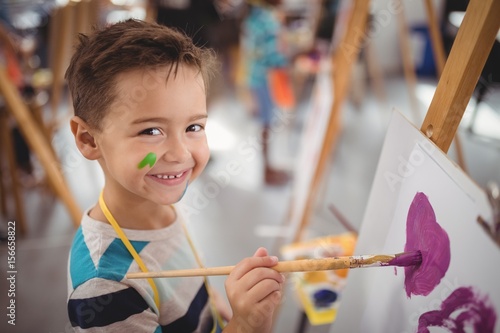 Portrait of happy schoolboy panting on canvas photo