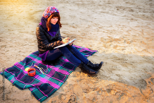 beautiful girl sitting on the beach and has records in a noteboo photo