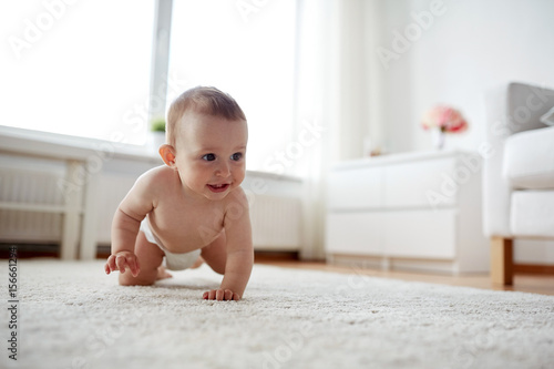 фотографія little baby in diaper crawling on floor at home
