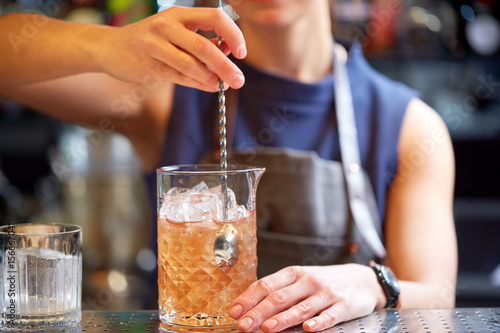 Obraz na płótnie bartender with cocktail stirrer and glass at bar