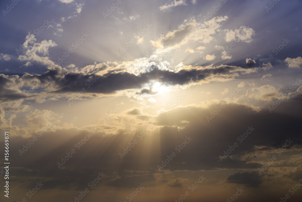 Fototapeta premium Empty cloudy sky from orange to blue with sun rays during the sunset