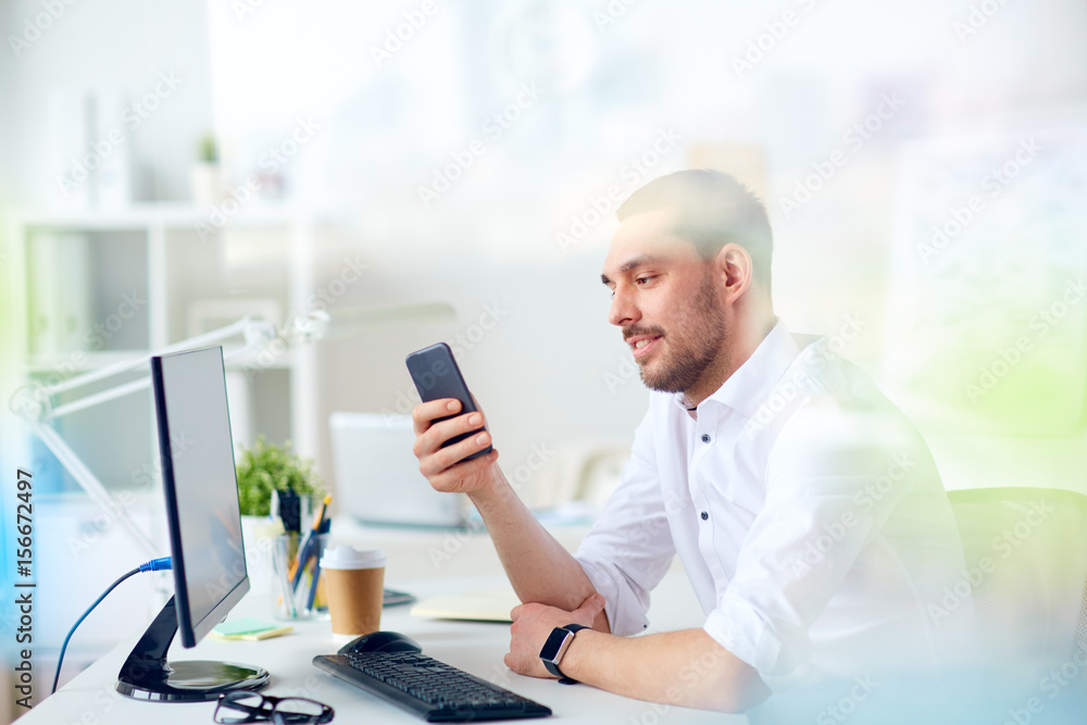 businessman with smartphone and computer at office