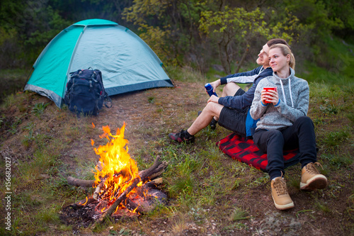 Young happy couple hiking in forest. Smiling couple resting enjoying a break during hike vacations. Camping  travel  tourism  hike and people concept.