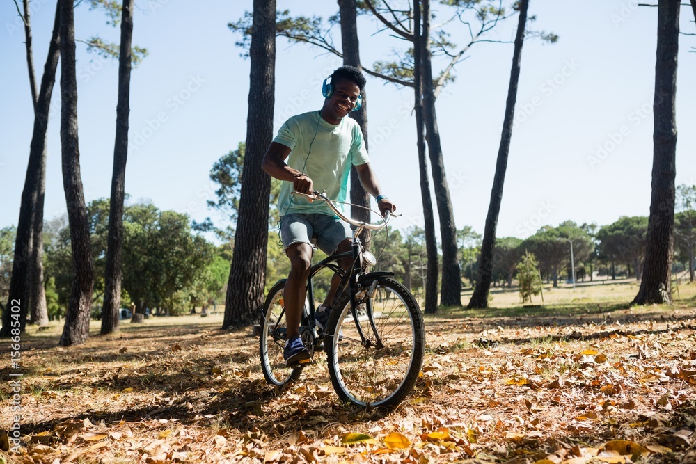 Fototapeta premium Man with headphones riding bicycle in the park