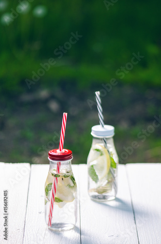 Refreshing homemade flavored water with lemon, lime and mentha on a white table in garden. Summer time. Beverages.