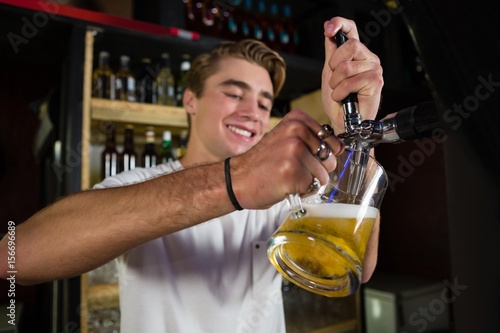 Happy bartender preparing beer