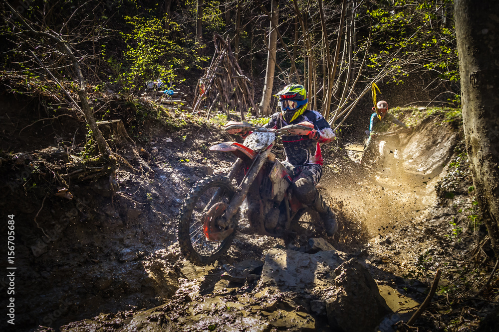 Obraz na plátně Motocross rider passes through the mud on the hardenduro race