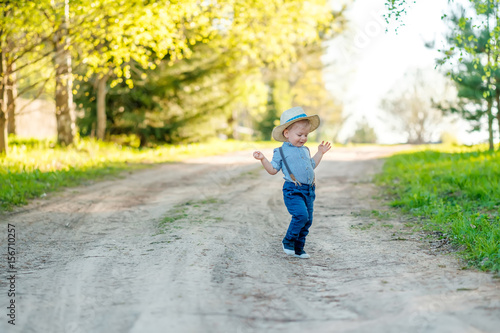 Toddler child outdoors. Rural scene with one year old baby boy wearing straw hat