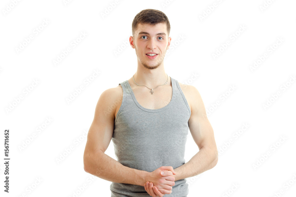 charming young guy standing in the grey t-shirt looks forward and smiling charming young guy standing in the grey t-shirt looks forward and smiling