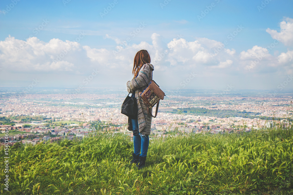 Traveling woman with a backpack looking far away on a mountain