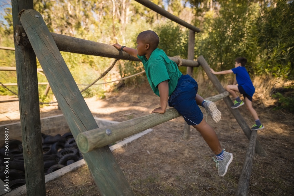 Fototapeta premium Boys exercising on outdoor equipment during obstacle course