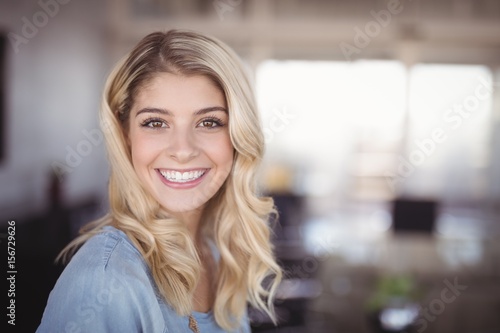 Fototapeta Smiling business woman standing in creative office