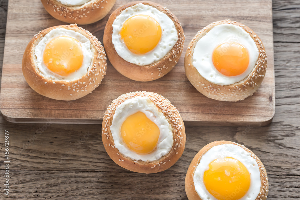 Egg-in-a-hole buns on the wooden board Egg-in-a-hole buns on the wooden board