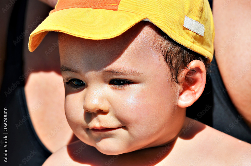Little happy boy, playing in the pool, on his mother's lap on sunny day.
