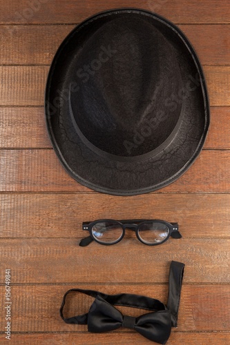 Hat, spectacles and bow tie arranged on wooden background