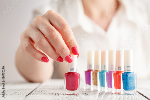 Close up of woman hands with nail polishes of different colors