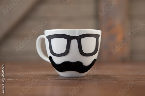 Fake moustache and spectacles on cup