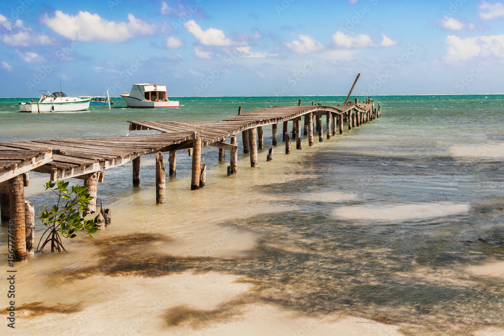 Wooden pier dock, boats and ocean view at Caye Caulker Belize Caribbean.