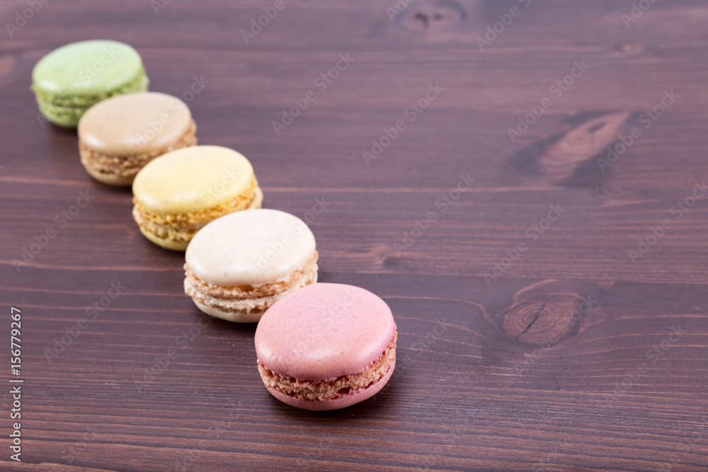 Five tasty and colorful macaroons on a natural ipe wood dark brown table Five tasty and colorful macaroons on a natural ipe wood dark brown table