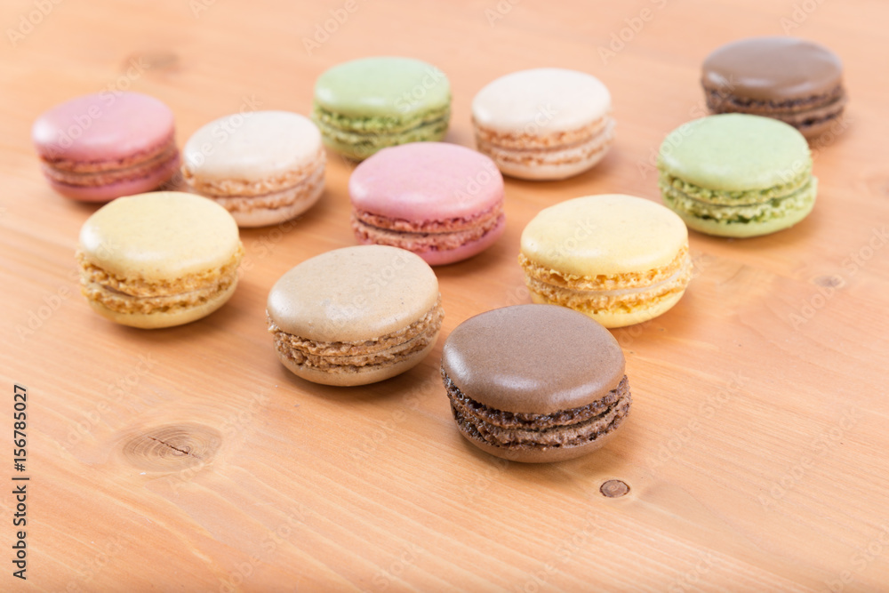 Fresh and tasty and colorful macaroons on a natural oak wood brown table - form of a triangle
