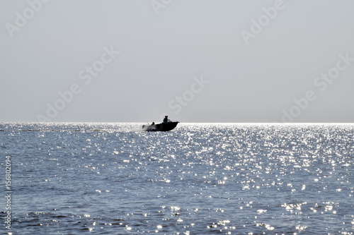 The boat rushes by the sea. In the boat people. Seascape in the evening. Silhouette of a motor boat and people in it against the background of the sea distance