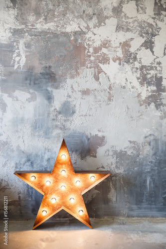 metal star with lamps near gray plaster wall in studio