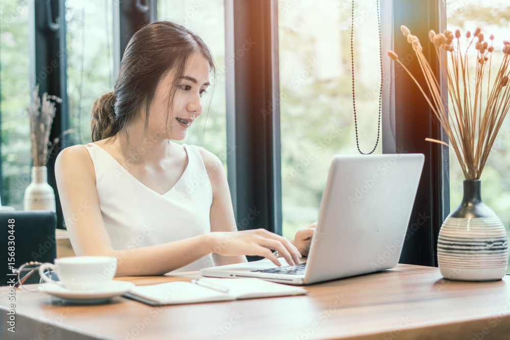 Fototapeta premium Young woman using laptop computer. Female working on laptop in a coffee shop.