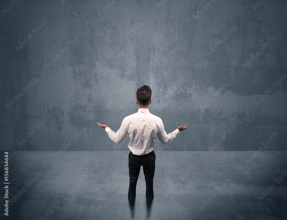 Businessman standing in front of urban wall Businessman standing in front of urban wall