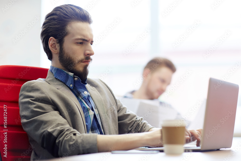 Obraz premium Serious office worker typing at workplace